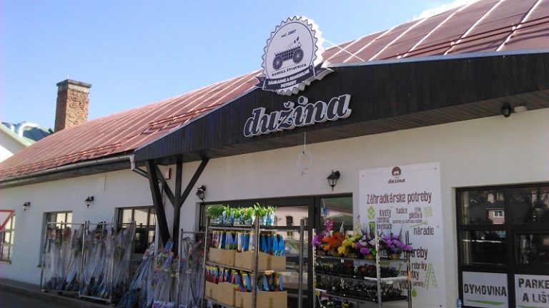Obrázok predajne s názvom "Dužina", zobrazuje vonkajší pohľad na budovu s červenou strechou a regálmi s kvetinami pred vstupom.